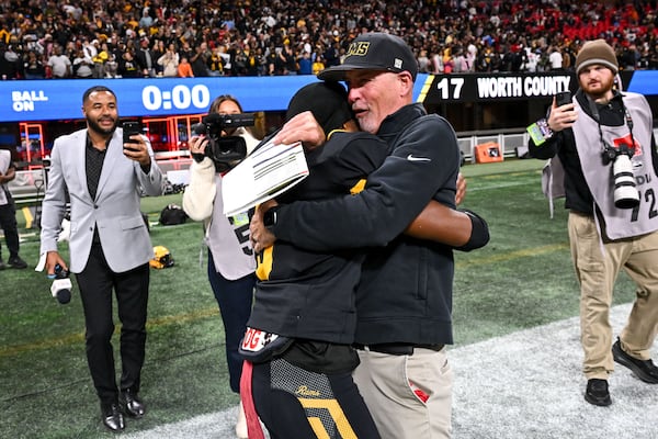 Worth County head coach Jeff Hammond hugs running back Khalijah Thomas after the Rams beat the Bulldogs 17-13 in a Class A Division I state championship game Tuesday, Dec. 16, 2025 at the Mercedes-Benz Stadium. (Daniel Varnado for the AJC)