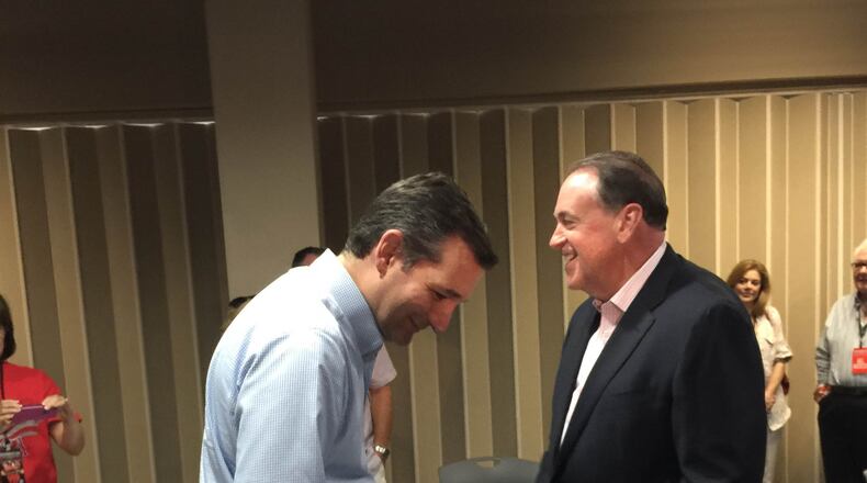 Texas Sen. Ted Cruz and former Arkansas Gov. Mike Huckabee share a private word before taking the stage at a Georgia megachurch. AJC Special.