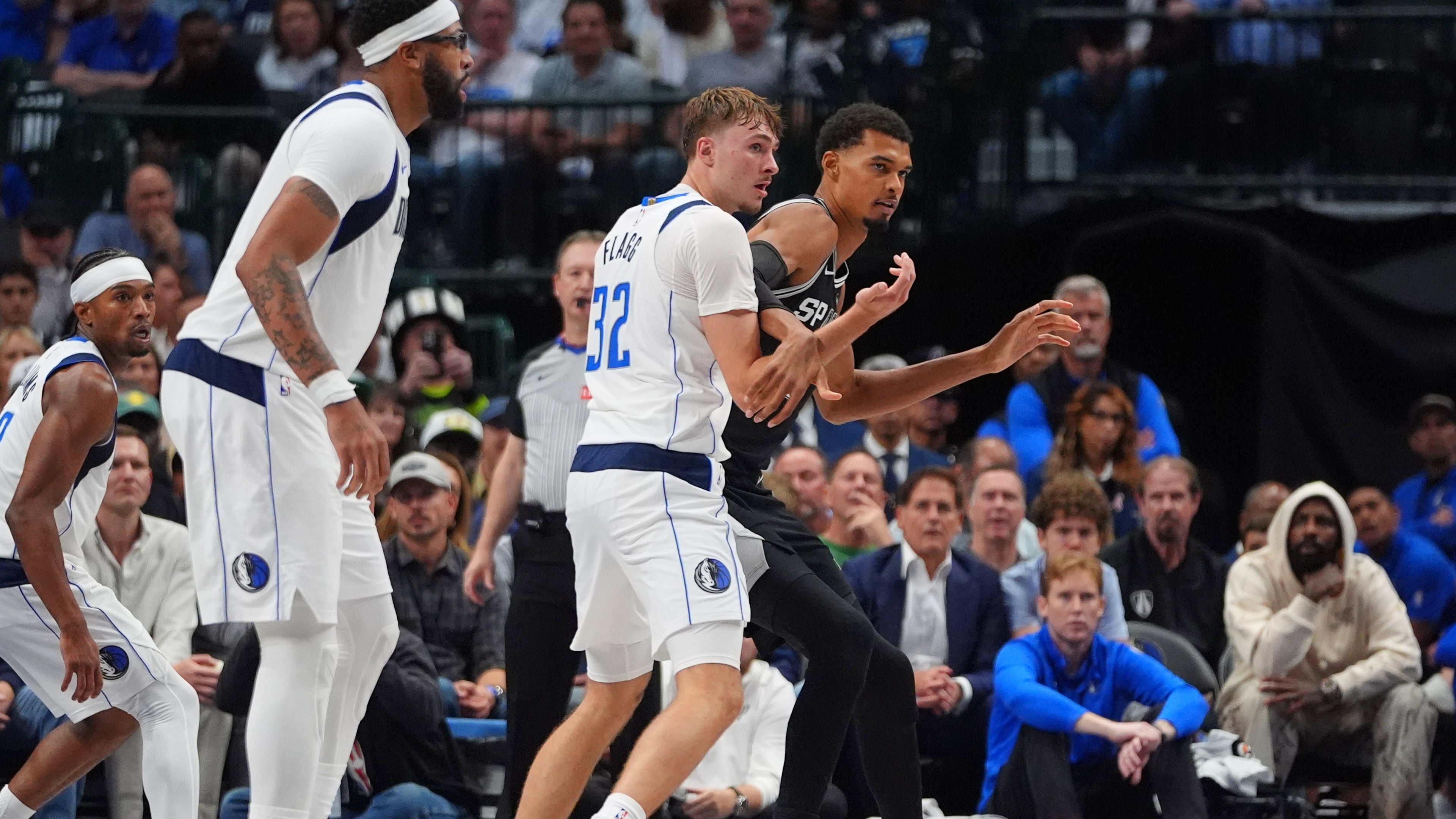 San Antonio Spurs forward Victor Wembanyama, right, is defended by Dallas Mavericks forward Cooper Flagg (32) as forward Anthony Davis, second from left, looks on during the second half of an NBA basketball game in Dallas, Wednesday, Oct. 22, 2025. (AP Photo/LM Otero)