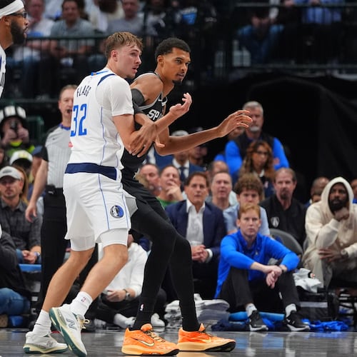 San Antonio Spurs forward Victor Wembanyama, right, is defended by Dallas Mavericks forward Cooper Flagg (32) as forward Anthony Davis, second from left, looks on during the second half of an NBA basketball game in Dallas, Wednesday, Oct. 22, 2025. (AP Photo/LM Otero)