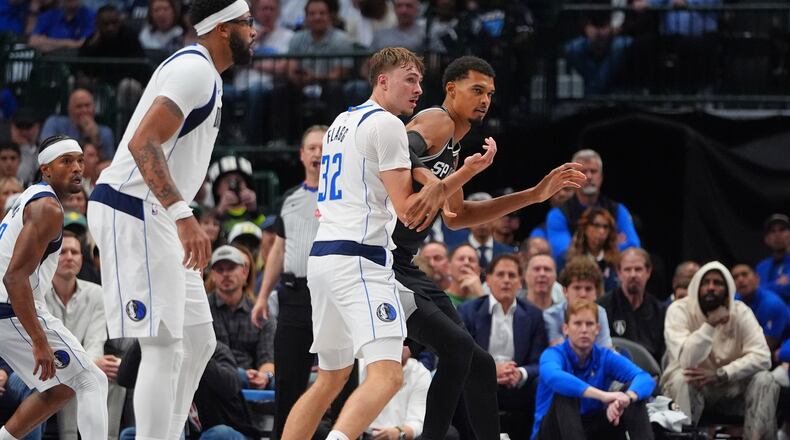 San Antonio Spurs forward Victor Wembanyama, right, is defended by Dallas Mavericks forward Cooper Flagg (32) as forward Anthony Davis, second from left, looks on during the second half of an NBA basketball game in Dallas, Wednesday, Oct. 22, 2025. (AP Photo/LM Otero)