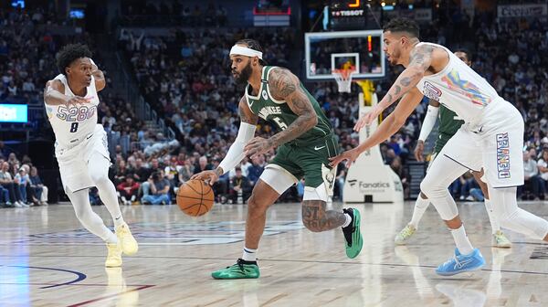 Milwaukee Bucks guard Gary Trent Jr., center, drives to the basket between Denver Nuggets forwards Peyton Watson, left, and Michael Porter Jr. in the first half of an NBA basketball game Wednesday, March 26, 2025, in Denver. (AP Photo/David Zalubowski)
