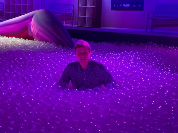 Exhibition Hub chief creative officer John Zaller gets insides a pool packed with bubble-like plastic balls. (Rodney Ho/AJC)