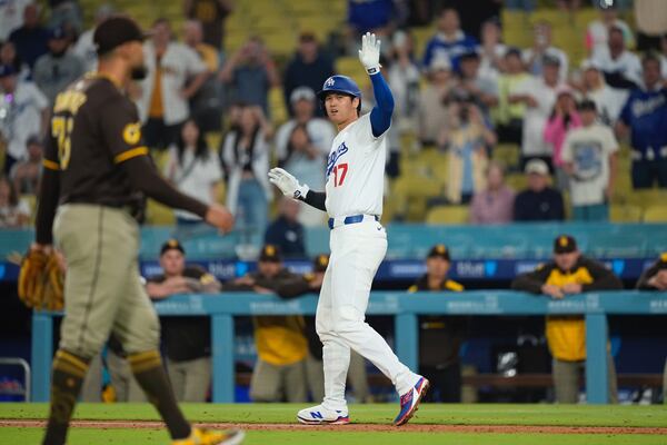 Los Angeles Dodgers' Shohei Ohtani, right, waves toward the dugout after being hit by a pitch thrown by San Diego Padres relief pitcher Robert Suarez, left, during the ninth inning of a baseball game Thursday, June 19, 2025, in Los Angeles. (AP Photo/Mark J. Terrill)