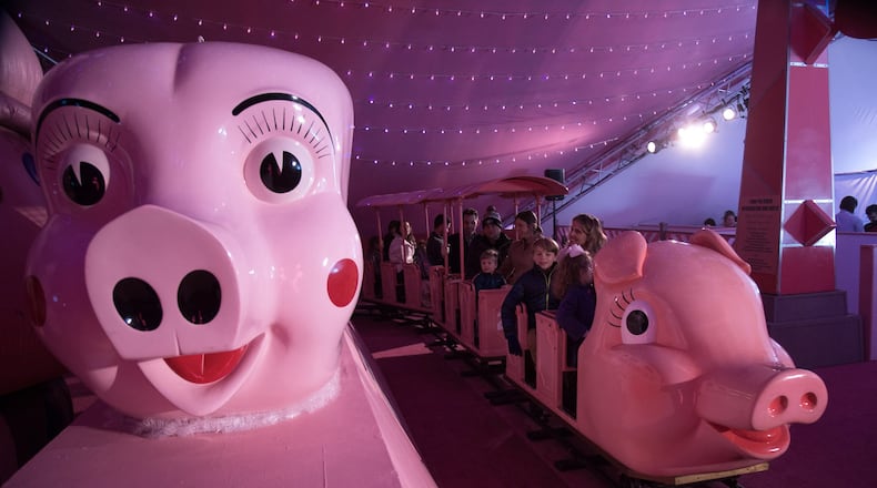A pink train full of people makes it’s way around the track beneath a 170-foot, 1950s-themed Macy’s Pink Pig tent in this file photo. STEVE SCHAEFER / SPECIAL TO THE AJC