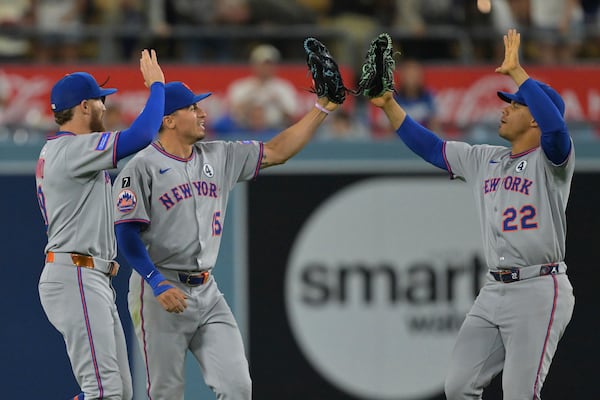 New York Mets left fielder Brandon Nimmo, left, Mets center fielder Tyrone Taylor and Mets right fielder Juan Soto (22) high five after the final out in the tenth inning of a baseball game against the Los Angeles Dodgers, Monday, June 2, 2025, in Los Angeles. (AP Photo/Jayne Kamin-Oncea)