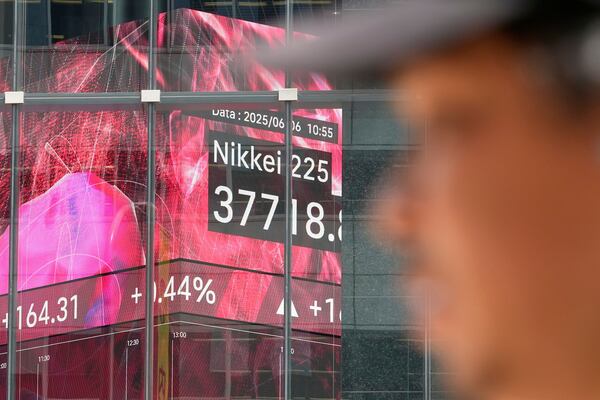 A person walks in front of an electronic stock board showing Japan's Nikkei index at a securities firm Friday, June 6, 2025, in Tokyo. (AP Photo/Eugene Hoshiko)