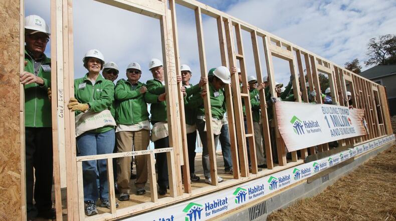 Past and present Habitat for Humanity International Board members hold the wall of the organization’s 800,000th house built, rehabilitated or repaired worldwide. Roswell has awarded $237,964 for a Habitat project in that city. AJC FILE / BOB ANDRES