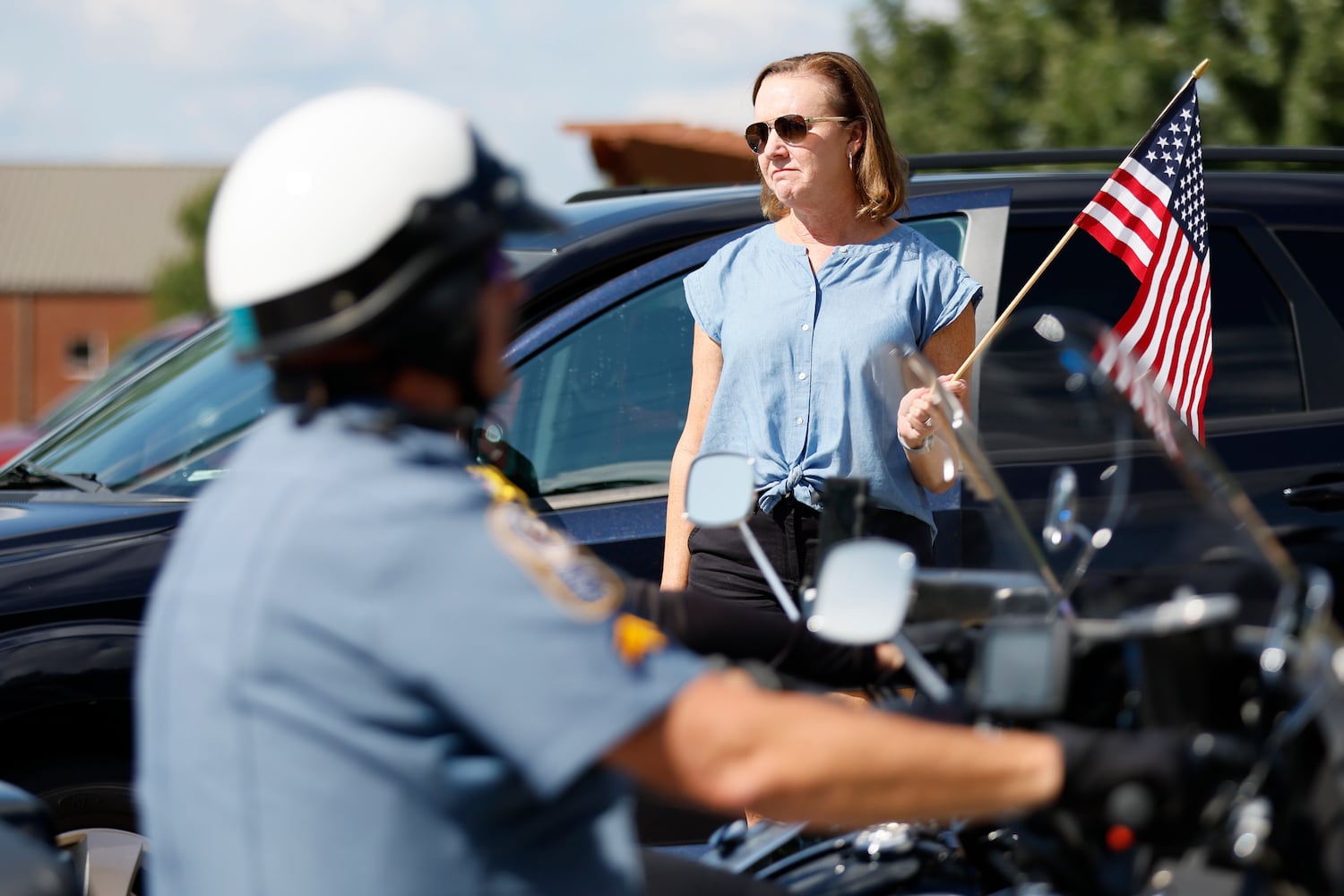 A visibly moved woman holds an American flag as she watches the procession of fallen Marshal Samual Ervin Jr go by Dallas Highway on Thursday, September 15, 2022, in Dallas, Ga. Thursday, September 15, 2022. Miguel Martinez / miguel.martinezjimenez@ajc.com 