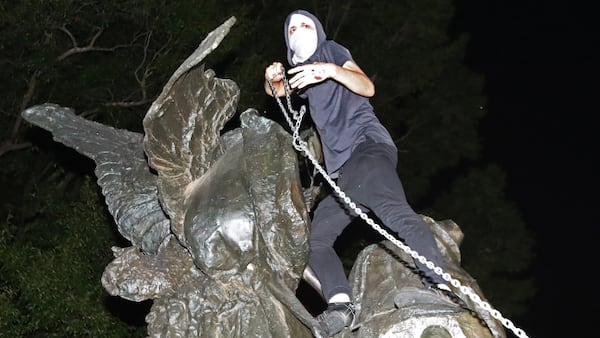 After marching from Woodruff Park to Piedmont Park during a anti white nationalism memorial and march in response to violence in Virginia, a protester climbs a Confederate monument with a chain in an attempt to topple it on Sunday, Aug. 13, 2017, in Atlanta. The peace monument at the 14th Street entrance depicts a angel of peace stilling the hand of a Confederate soldier about to fire his rifle. (Curtis Compton/Atlanta Journal-Constitution)