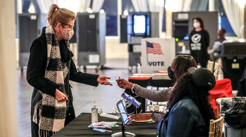 November 30, 2021 Atlanta: Sonya Collins (left) receives her ballot from poll workers, Brandy Allen (center) and Quay Edwards (right) at Park Tavern located at 500 10th St NE in Atlanta on Tuesday, November 30,2021. The runoff election that will set the course for the next four years at Atlanta City Hall will be decided Tuesday, as voters went to the polls to elect the cityÕs 61st mayor. Tuesday caps off a historic election cycle that saw the incumbent mayor forego a reelection bid and a former mayor seek a third term at City Hall. The race ends with two City Council colleagues on the ballot for mayor: Councilman Andre Dickens and City Council President Felicia Moore, who both have big plans to bolster the ranks of the police department, improve basic city services and reopen City Hall to the public. Dickens, a southwest Atlanta native, is a two-term citywide councilman aiming to repair the Òsoul of AtlantaÓ through a number of proposed new initiatives and city departments. Moore, 24-year veteran of the council, is pitching her decades of civic service and legislative experience as prime reasons she should lead the city. Both canvassed AtlantaÕs neighborhoods in the final days of the runoff, hoping to energize residents and encourage voter turnout after a sleepy holiday week. (John Spink / John.Spink@ajc.com)
