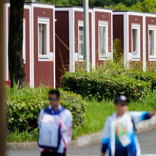 Officials stand outside the athletes accommodation huts at the Athletes Village ahead of the Asian Games Nagoya, Japan, Friday, Sept. 18, 2026. (AP Photo/Dita Alangkara)