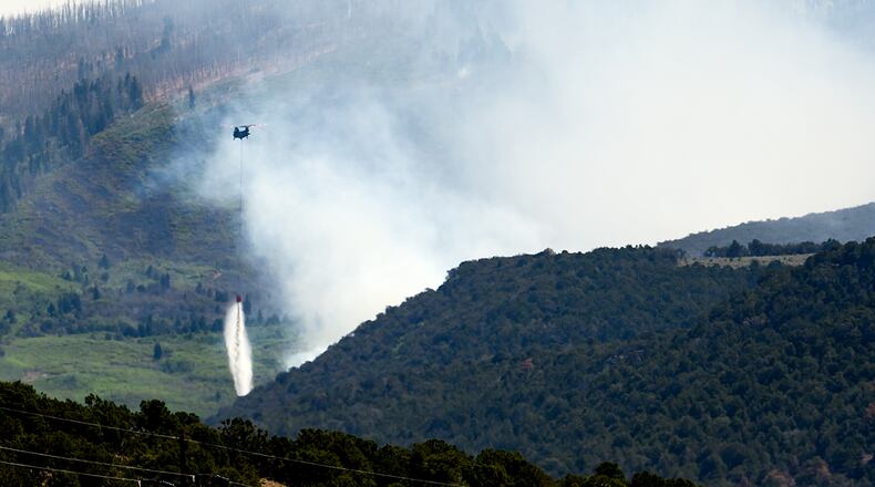 A helicopter drops water on the Cottonwood Fire burning near Beaver, Utah, on Saturday, June 27, 2026. (AP Photo/Noah Berger)