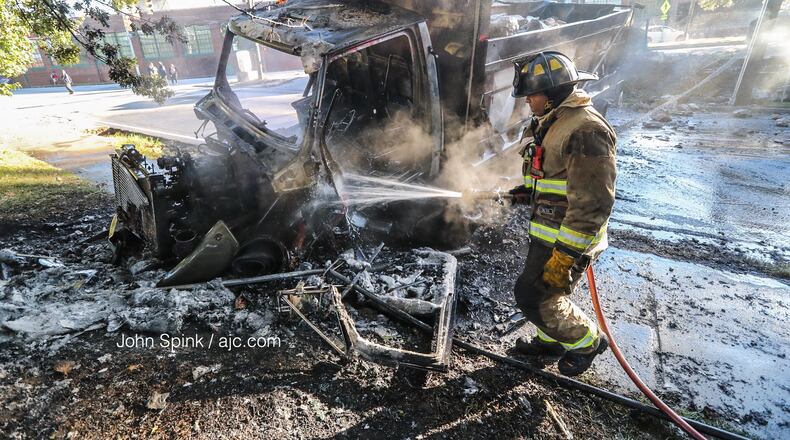 An Atlanta firefighter works to put out hot spots after a dump truck crashed into several vehicles, went over a 6-foot retaining wall and burst into flames in northwest Atlanta early Wednesday.