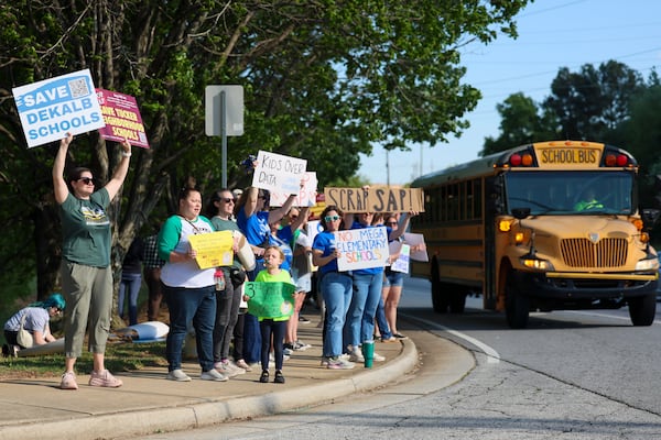 Parents and students from schools all over the district rally against proposed school closures along Mountain Industrial Boulevard as a DeKalb County School bus turns into the DeKalb County School Board property in Stone Mountain on Monday, April 20, 2026. (Jason Getz/AJC)