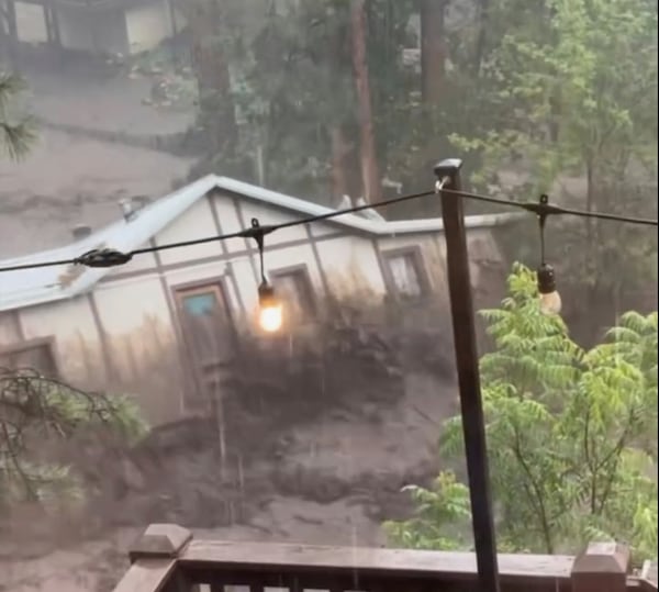 In this image taken from video, a house is carried away by flash flooding behind a house in Ruidoso, N.M., Tuesday, July 8, 2025. (Kaitlyn Carpenter via AP)