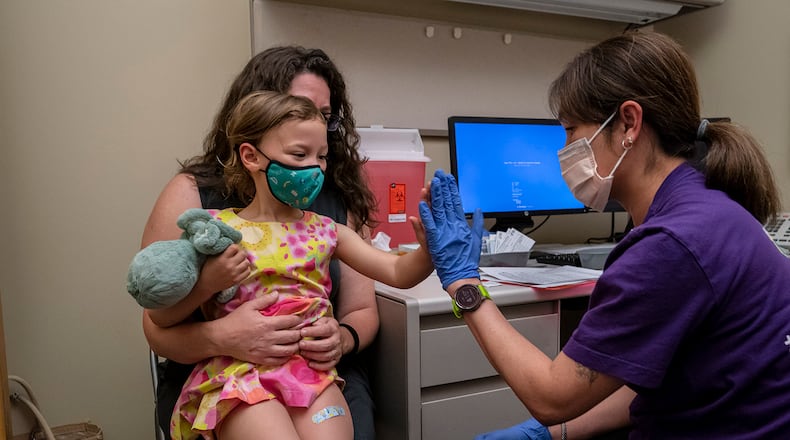 Nora Burlingame, 3, sits on the lap of her mother, Dina Burlingame, and gets a high five from nurse Luann Majeed after receiving her first dose of the Pfizer COVID-19 vaccination at UW Medical Center - Roosevelt on June 21, 2022, in Seattle. (David Ryder/Getty Images/TNS)