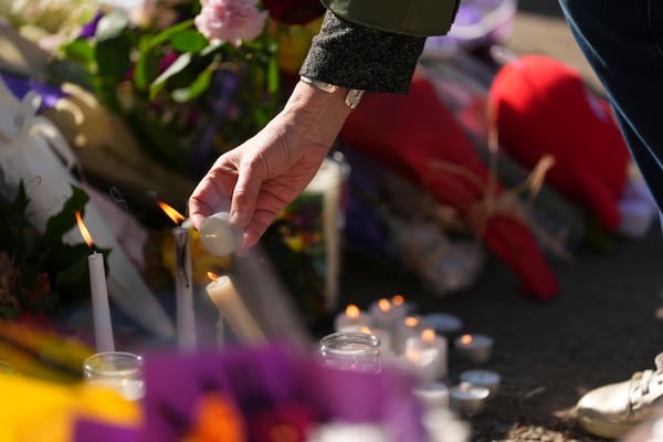 A person lights a candle at a memorial after a vehicle drove into a crowd during a Filipino heritage festival in Vancouver, British Columbia, Sunday, April 27, 2025. (AP Photo/Lindsey Wasson)