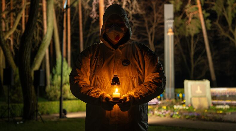 A man dressed in white protective suits holds a candle during a memorial service dedicated to firefighters and workers who died after the 1986 Chornobyl (Chernobyl) nuclear disaster, ahead of its 40th anniversary in Slavutych, Ukraine, Saturday, April 25, 2026.Chornobyl is the Ukrainian name for the city. (AP Photo/Dan Bashakov)