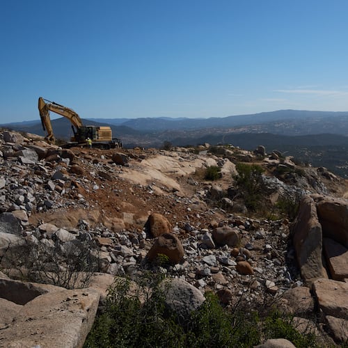 Construction crews work on a new border wall segment on Kuuchamaa Mountain, Friday, April 24, 2026, seen from Tecate, Mexico. (AP Photo/Gregory Bull)