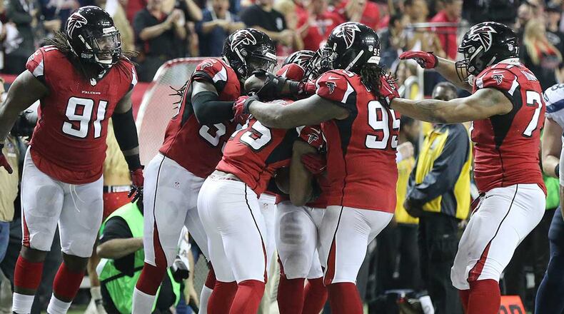 Falcons defenders swarm linebacker Deion Jones after his interception in the final minutes of Saturday's win over the Seahawks.