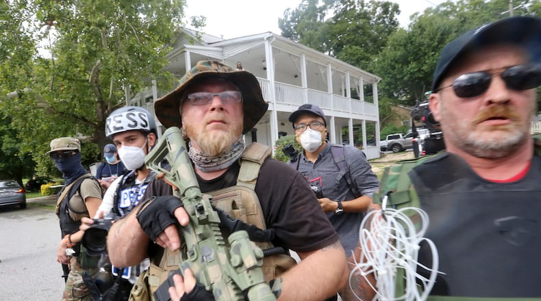 Georgia Security Force III% militia leader Chris Hill (center) stands with allies at a rally Saturday, Aug. 15, 2020, in Stone Mountain, Georgia, while a broad coalition of leftist anti-racist groups organized a counter-demonstration. (Jenni Girtman/Atlanta Journal-Constitution/TNS)