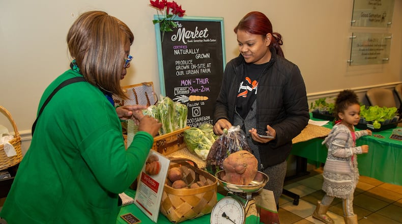 Market manager Loren Ferguson helps Anileidi Gomez buy vegetables at the Market in the lobby of the Good Samaritan Health Center in Atlanta. The center employs farmers to tend their urban farm near downtown so patients and people in the community have access to healthy food options. CONTRIBUTED BY PHIL SKINNER