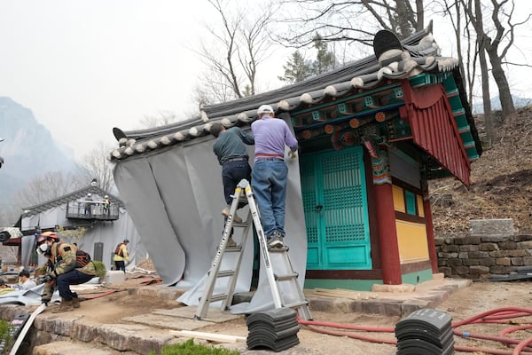 Workers cover temples with fireproof fabric in preparation for a possible approaching wildfire at a temple in Cheongsong, South Korea, Thursday, March 27, 2025. (AP Photo/Ahn Young-joon)