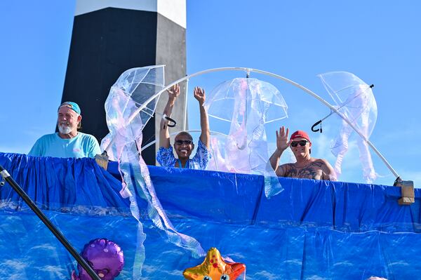 Beach Bum Parade participants wave and cheer as they wait for the start of the parade in the staging area behind the iconic Tybee Light House. (Sarah Peacock for the AJC)
