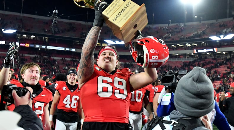 Georgia offensive lineman Tate Ratledge (69) holds up the Governor's Cup trophy after Georgia won 44-42 over Georgia Tech in eight overtimes during an NCAA football game at Sanford Stadium, Friday, November 29, 2024, in Athens. (Hyosub Shin / AJC)
