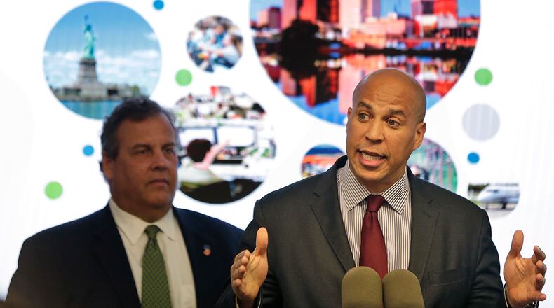 FILE - In this Monday, Oct. 16, 2017, file photo, New Jersey Sen. Cory Booker, right, speaks while New Jersey Gov. Chris Christie stands behind him during an announcement in Newark, N.J. The New Jersey lawmakers announced they are submitting a bid to Amazon that Newark would be the best location for the company's planned second headquarters. (AP Photo/Seth Wenig, File)