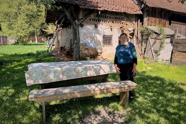 Liliana Cosurean, 54, stands in the yard of her home, in the village of Floresti, in Romania's central Transylvania region, Thursday, April 24, 2025. (AP Photo/Stephen McGrath)