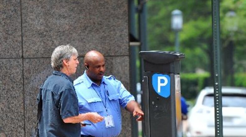 Kevin Brown with PARKAtlanta helps Bruce Goldsmith figure out the parking meter pay station in this August 2012 photo. Atlanta’s City Council tabled a vote Monday on a new parking enforcement vendor to replace PARKAtlanta, whose ticketing practices raised the ire of many motorists. BRANT SANDERLIN / BSANDERLIN@AJC.COM