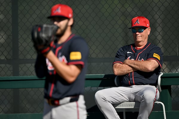 Braves manager Brian Snitker (right) watches pitcher Ian Anderson during spring training workouts.