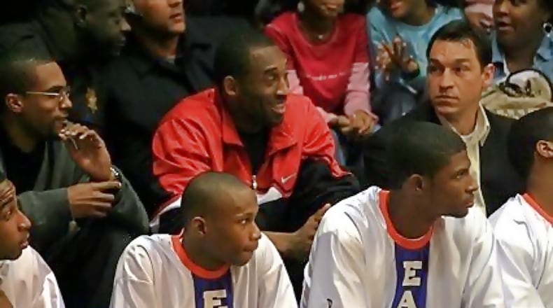 Kobe Bryant (in red) sits behind the Columbia boys basketball bench during a game Feb. 5, 2007. To Bryant's left is Rob Pelinka, his agent at the time, now  general manager of the Lakers. The Columbia players (from left) are Allen Moorer, Steve Lattimore and Antonio Wilson. Photo: DeKalb County Athletics