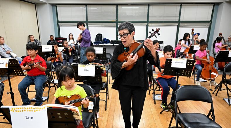 Juana Alzaga (standing) instructs members of the Buford Highway Orchestra Project at the Latin American Association in Brookhaven on Thursday, Nov. 6, 2025. The orchestra, which is comprised mostly of children of parents who lack legal status, will be featured in the documentary “La Orquesta” coming this month to PBS. (Hyosub Shin/AJC)