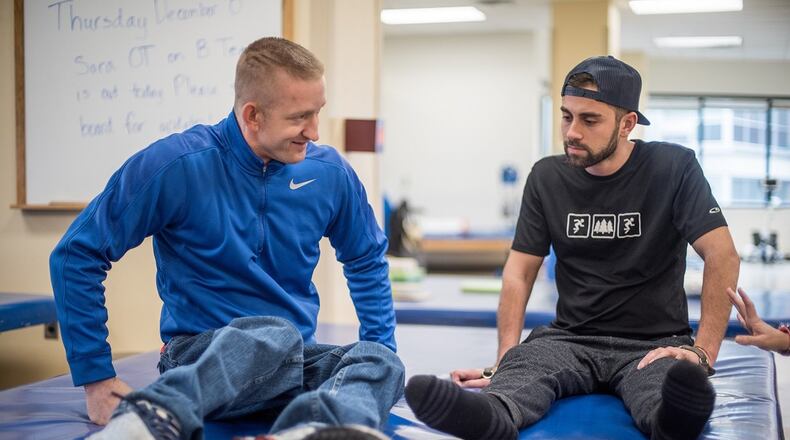 Talbot Kennedy (left) shows Shepherd Center patient George Casares some stretching exercises. LOUIE FAVORITE