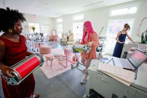 Workshop instructor Arantza Peña Popo (left) and studio founder Samantha Richardson (center) change Risograph machine ink drums at Posy Press while studio assistant Maddy Lyons works on a Riso print on another machine. (Miguel Martinez/AJC)