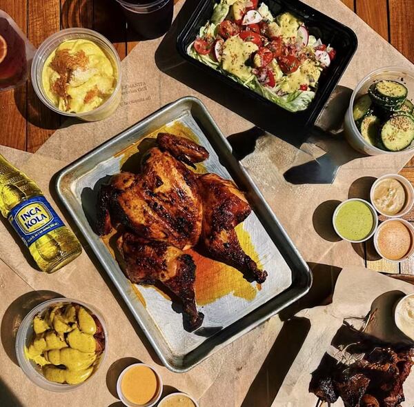 A smoked spatchcocked chicken is displayed on a sheetpan. Dishes of sauces, a salad and vegetables are artfully arranged around the sheetpan.