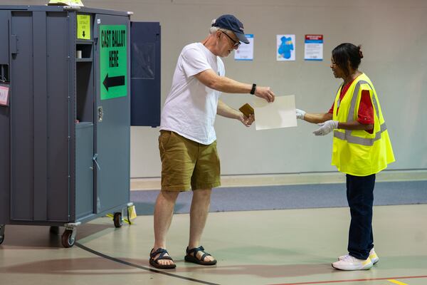 At a polling place in Cobb County, a voter turns in his ballot during the Democratic primary runoff for Georgia’s Public Service Commission on Tuesday, July 15, 2025. (Olivia Bowdoin/AJC)