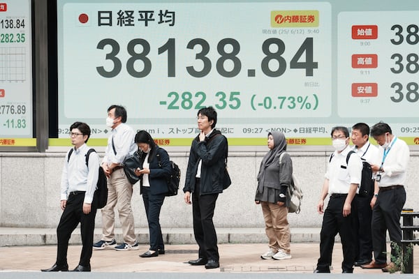 People stand in front of an electronic stock board showing Japan's Nikkei index at a securities firm Thursday, June 12, 2025, in Tokyo. (AP Photo/Eugene Hoshiko)