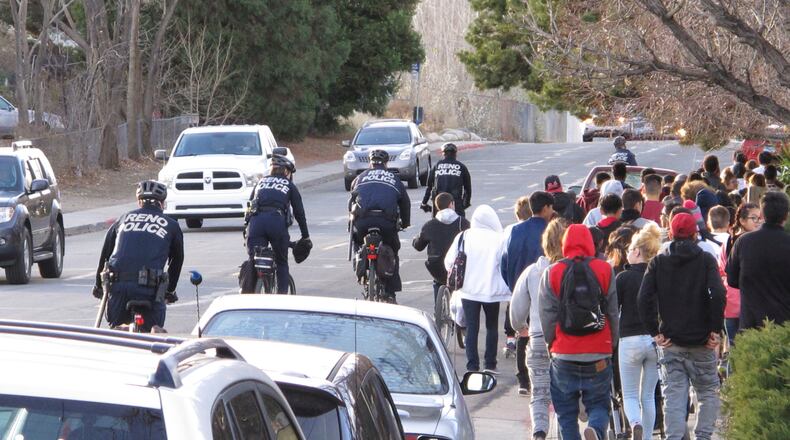 Reno police officers on bicycles escort about 100 protesters as they march 2 miles to the Washoe County School District headquarters to deliver a petition on non-lethal force after a 14-year-old Reno boy was shot last week by a campus police officer, Wednesday, Dec. 14, 2016, in Reno, Nev.. (AP Photo/Scott Sonner)