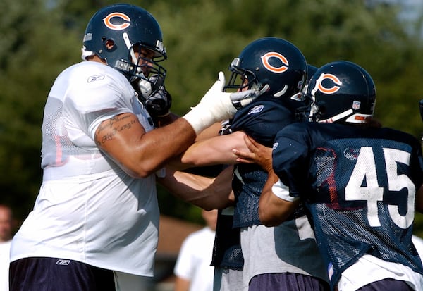 FILE - Chicago Bears' Aaron Gibson, left, and Cameron Worrell, center, get into a brief scuffle as Virgil Williams (45) tries to separate the teammates during training camp Saturday, July 31, 2004, in Bourbonnais, Ill. (AP Photo/Jeff Roberson, File)