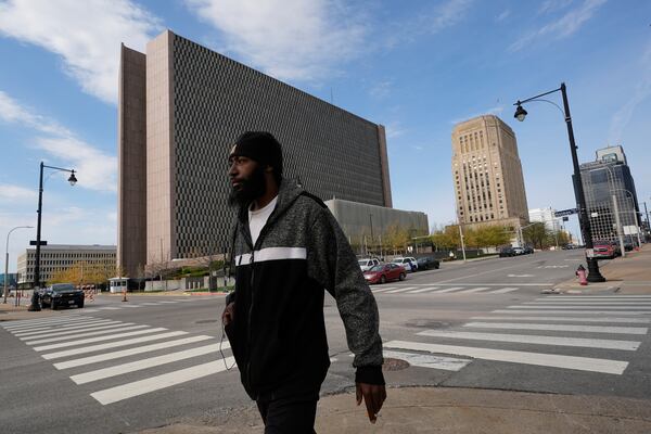 A pedestrian walks past the The Richard Bolling federal building, left, Monday, April 14, 2025, in Kansas City, Mo. (AP Photo/Charlie Riedel)