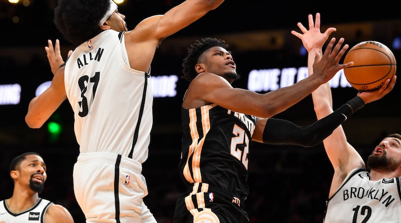 Hawks forward Cam Reddish (22) splits the defense of Brooklyn Nets center Jarrett Allen (31) and guard Joe Harris, right, during the second half of an NBA basketball game Wednesday, Dec. 4, 2019, in Atlanta. Brooklyn won 130-118. (AP Photo/John Amis)