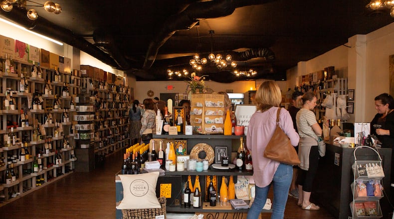 About 70% of the wine on the shelves at Wine & Whimseys on Main Street in Tucker comes from outside of the U.S., according to owner Bridget Brady, pictured here at the register. Brady fears proposed tariffs on imported wine might lead to higher prices that her customers cannot afford. (Courtesy of Bridget Elliott Brady)
