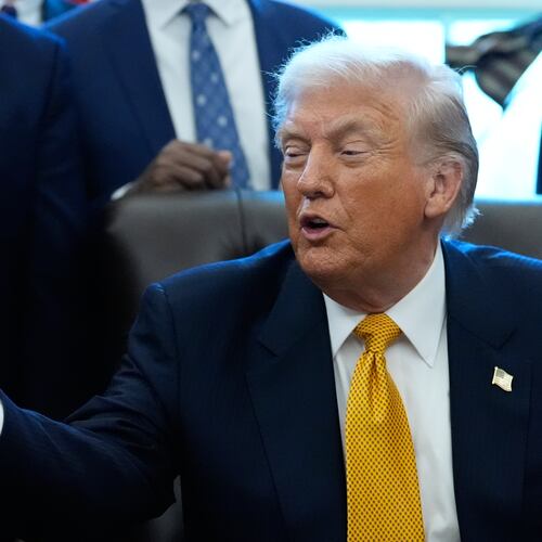 President Donald Trump gestures to a container of milk before he signs a bill that returns whole milk to school cafeterias across the country, in the Oval Office of the White House, Wednesday, Jan. 14, 2026, in Washington. (AP Photo/Alex Brandon)