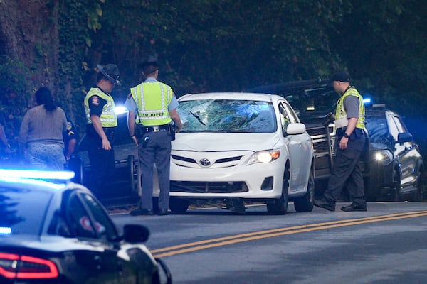 Georgia State Patrol troopers, who are investigating the incident, are seen focusing on a white Toyota sedan that had its windshield crushed on Thursday, Sept. 18, 2025. (Ben Hendren for the AJC)