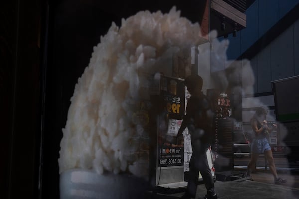 Pedestrians are reflected in the window of a restaurant advertising for rice in Tokyo, Thursday, May 22, 2025. (AP Photo/Louise Delmotte)