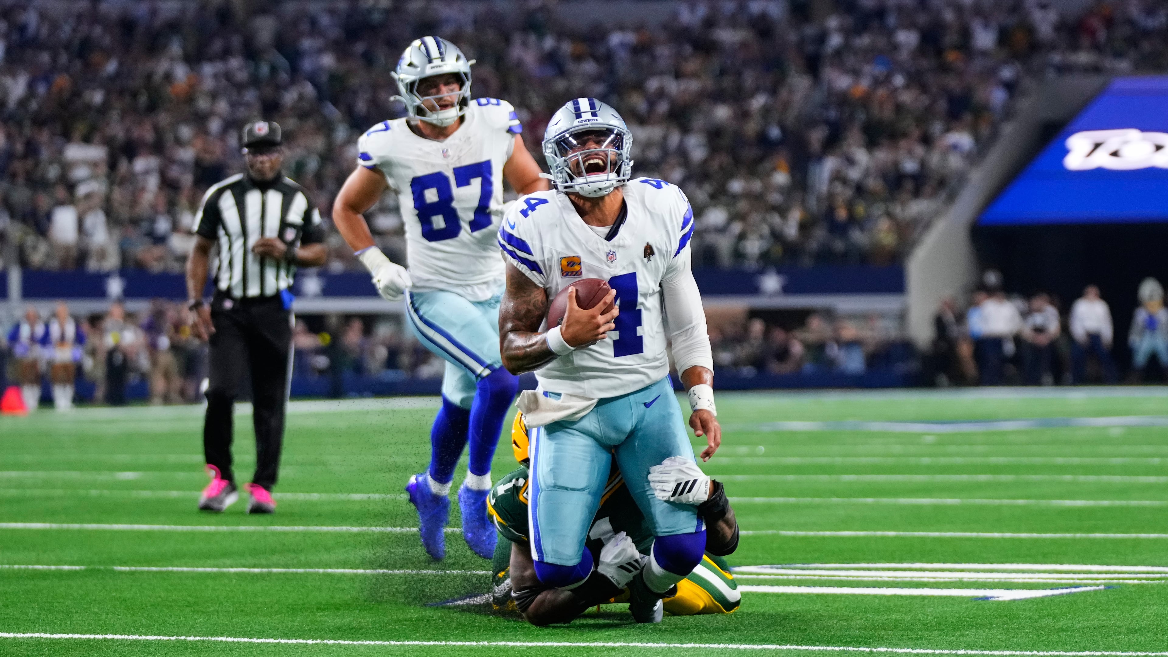Dallas Cowboys quarterback Dak Prescott (4) is stopped as he carries the ball by Green Bay Packers defensive end Micah Parsons, rear, in overtime of an NFL football game Sunday, Sept. 28, 2025, in Arlington, Texas. (AP Photo/Jeffrey McWhorter)